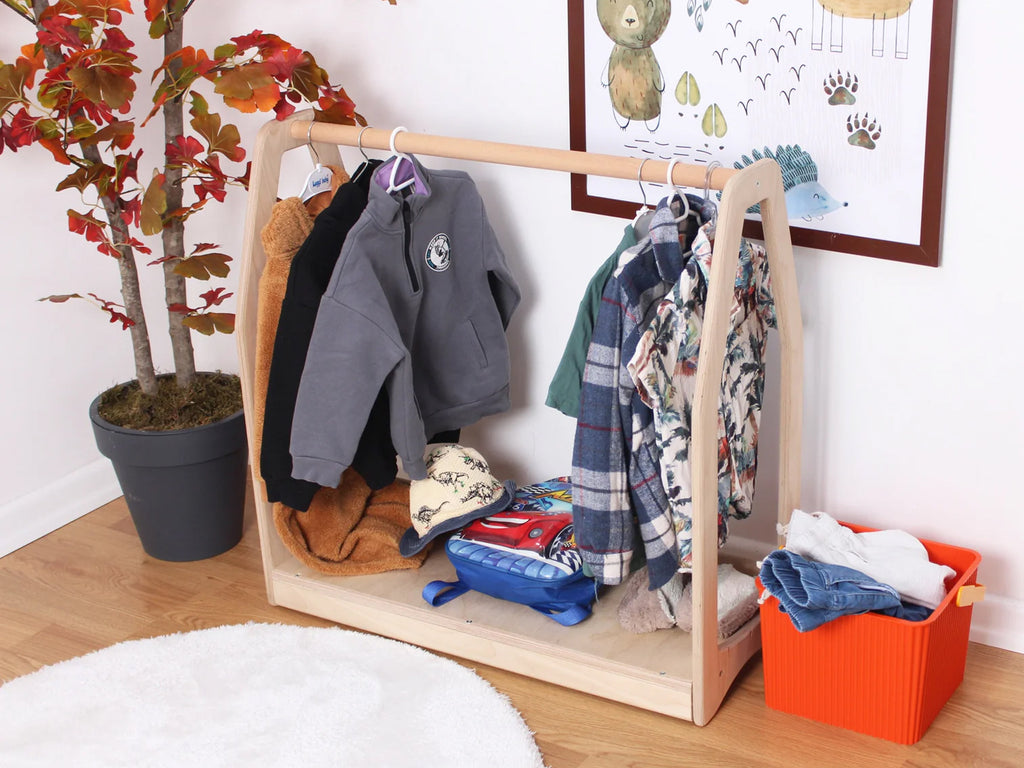 a child's clothing rack in a room with a potted plant