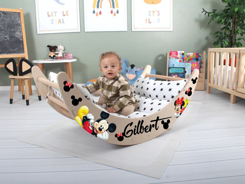 a baby sitting in a mickey mouse rocking chair