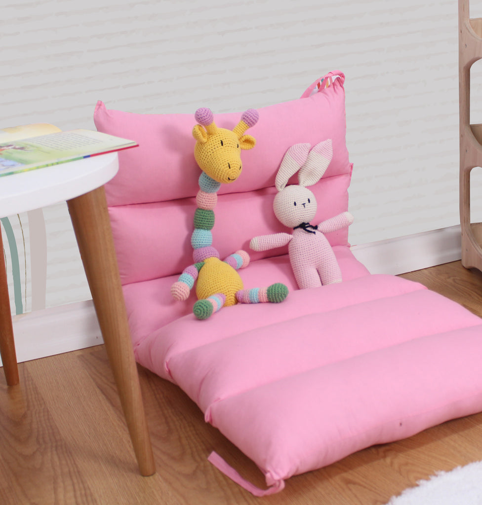 a pink chair with a stuffed animal and a giraffe on it