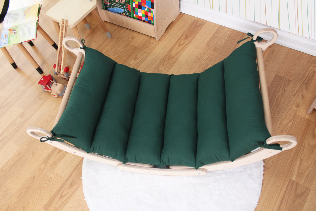 a child's swing bed with a green cushion