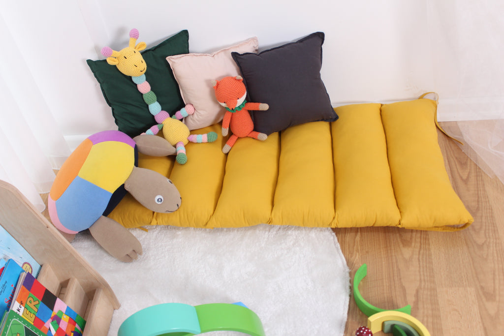 a child's play room with a yellow couch and stuffed animals