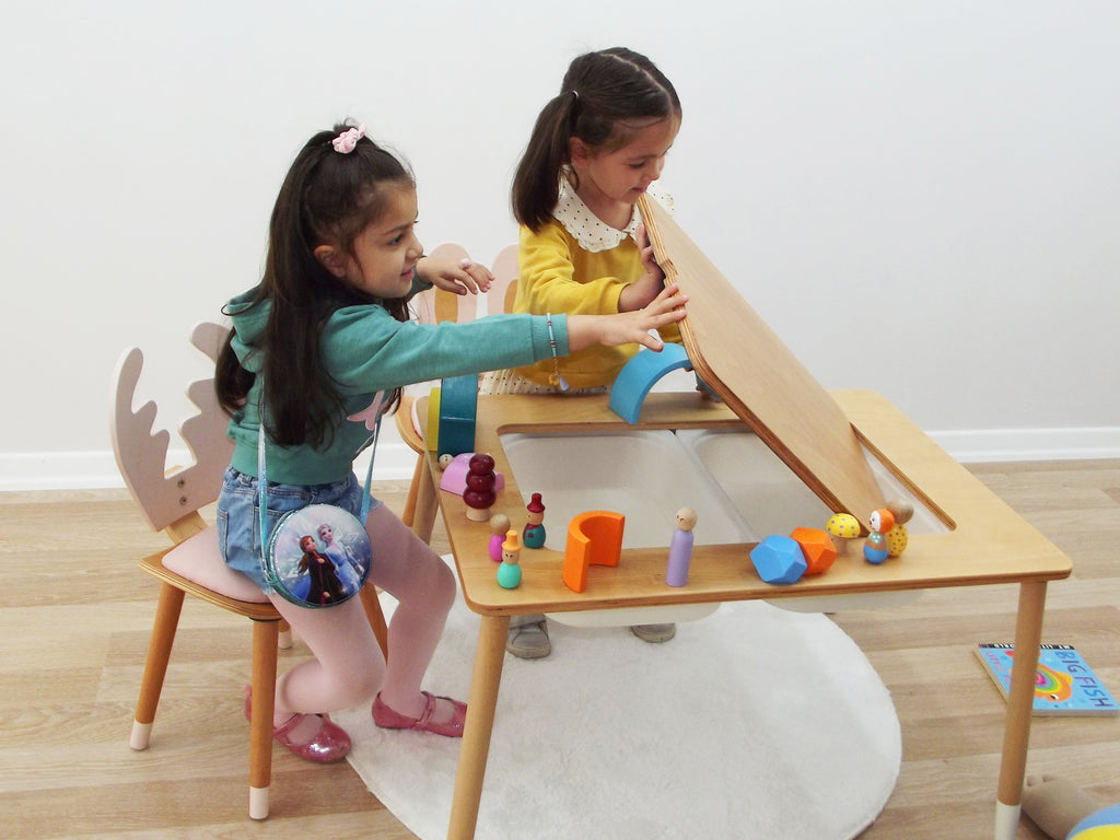 two little girls playing with a wooden table and chair