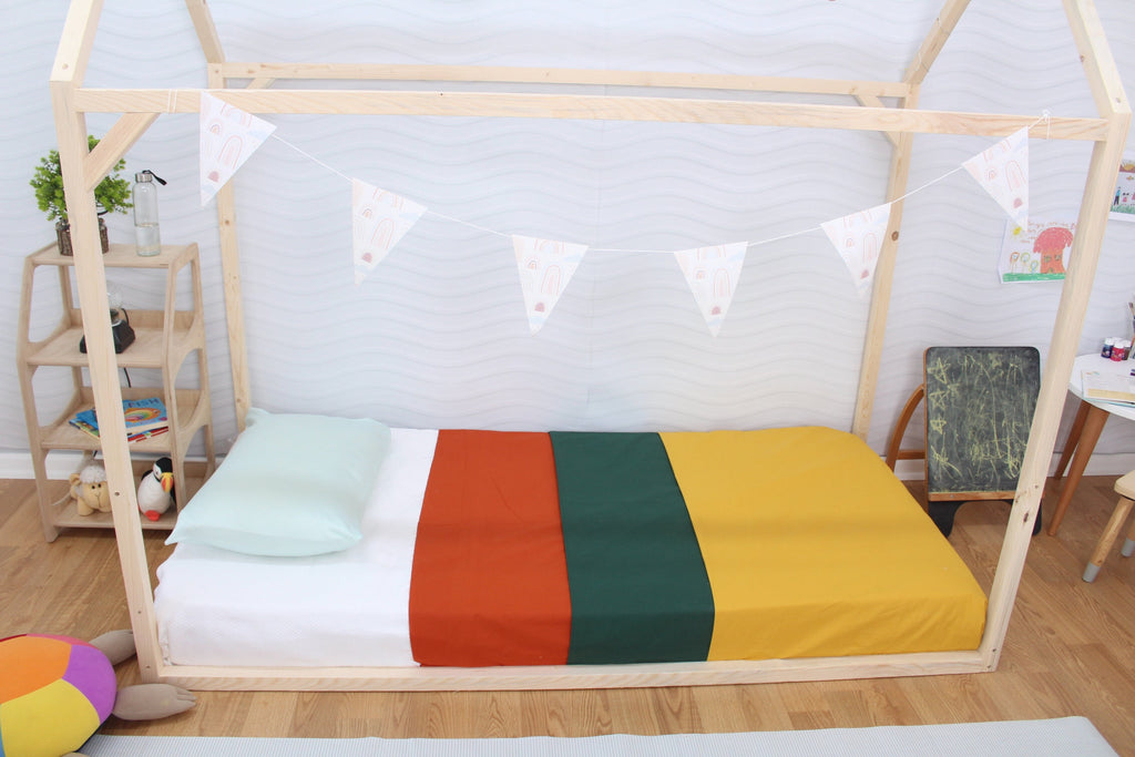 a child&#39;s bed with a rainbow blanket and pillows